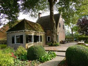 a stone house with a tree and a patio at de Boskpleats in Winsum