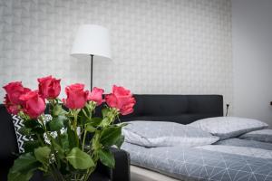 1 dormitorio con 1 cama y un jarrón con rosas rojas en Apartamenty AP 1 en Częstochowa