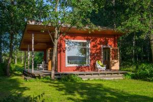 a small red cabin with a porch in the woods at Koivulan Kartano Cottage in Lohja