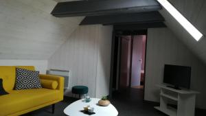 uma sala de estar com um sofá amarelo e uma televisão em Chez Mamie em Beynat