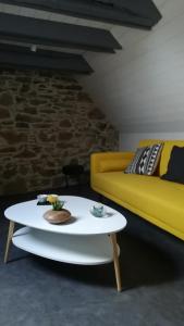 uma sala de estar com um sofá amarelo e uma mesa em Chez Mamie em Beynat