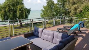 eine Terrasse mit einem Sofa, Stühlen und Meerblick in der Unterkunft Apartment Balaton in Siófok