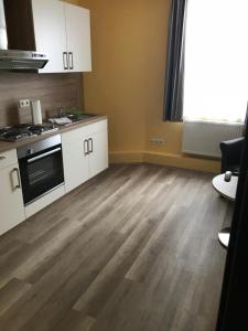 una cucina con armadietti bianchi e pavimenti in legno di Wolthusen a Emden