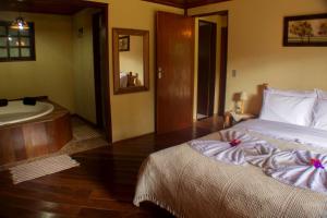 ein Schlafzimmer mit einem großen Bett und einer Badewanne in der Unterkunft Pousada da Carmem in Visconde De Maua