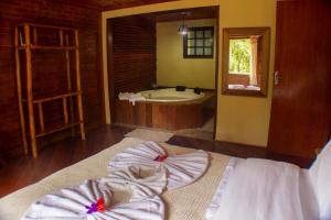 1 dormitorio con bañera y 1 cama con toallas en Pousada da Carmem, en Visconde De Maua