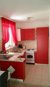 cocina con armarios rojos y estufa blanca en Apartments Zvono, en Slano