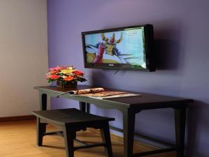 a table with a tv and a table with a stool at Sawasdee Hotel @ Sukhumvit Soi 8 in Bangkok