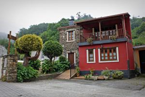 uma casa vermelha com uma varanda em cima em Apartamentos El Llago em Boal