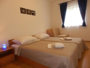 sypialnia z 2 łóżkami, krzesłem i oknem w obiekcie Apartment Greta w mieście Kanfanar