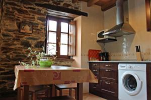 a kitchen with a table and a washing machine at Apartamentos El Llago in Boal