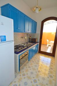 パトゥにあるCasa Spano 1 - RosariaVacanzeのキッチン(青いキャビネット、白い冷蔵庫付)