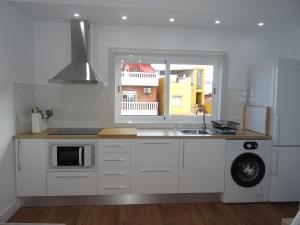 cocina blanca con fregadero y ventana en Carmen Apartamentos, en Málaga