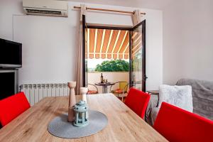 un soggiorno con tavolo in legno e sedie rosse di Apartman Lamanova a Rovigno (Rovinj)