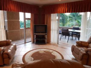 sala de estar con sofá, TV y mesa en Bubez Guesthouse, en Barberton