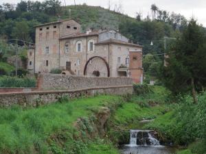 ein altes Gebäude auf einem Hügel neben einem Fluss in der Unterkunft Il Frantoio - a in Lucca