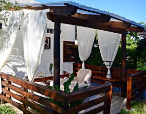 una terraza de madera con cenador y cortinas blancas en Esquina Apart Hotel en Esquina