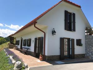 Casa blanca con ventanas negras y banco en Tourist farm Artisek, en Štore