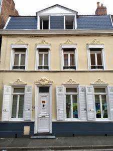un edificio amarillo con ventanas blancas contraventanas en Lumières B&B en Lille