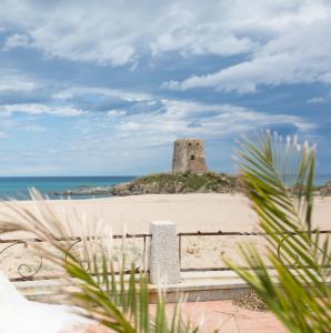 a building on an island in the sand on a beach at Il pergolato in Bari Sardo