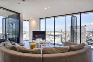 ein Wohnzimmer mit einem großen Sofa und großen Fenstern in der Unterkunft Apartmentsouthbank in Melbourne