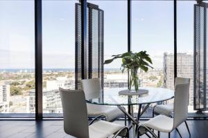 une salle à manger avec une table en verre et des chaises blanches dans l'établissement Apartmentsouthbank, à Melbourne