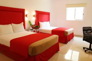 two beds in a hotel room with red and white at Hotel Zar Merida in Mérida