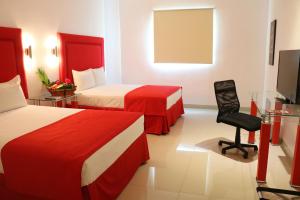um quarto de hotel com duas camas e uma cadeira em Hotel Zar Merida em Mérida