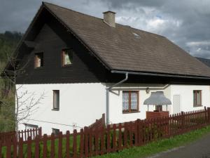 una casa blanca con techo negro y valla en Urlaub im Zirbenland, en Obdach