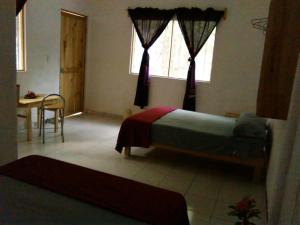 ein Schlafzimmer mit Bett, Tisch und Fenstern in der Unterkunft Posada Cielito Lindo in Mazunte