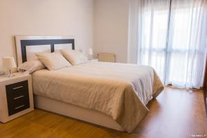 カンガス・デ・オニスにあるApartamento Principadoの白いベッドルーム(大型ベッド1台、ナイトスタンド付)