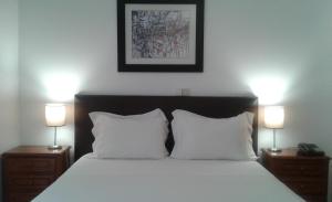 a bed with a white comforter and pillows at Hotel Tic Tac in Bragança