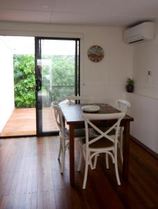 a dining room table with white chairs and a wooden floor at Boatsheds in Sawtell