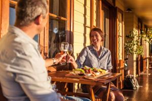 un hombre y una mujer sentados en una mesa con una copa de vino en Mudgee Homestead Guesthouse en Mudgee