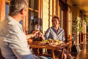 a man and woman sitting at a table with a glass of wine at Mudgee Homestead Guesthouse in Mudgee