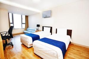 una habitación de hotel con 2 camas y una silla en Hyundai Residence, en Seúl