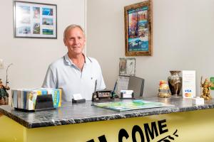 Un uomo in piedi davanti a un bancone di Tourist Court Motel a Whakatane