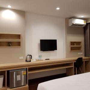 Zimmer mit einem Schreibtisch und einem TV an der Wand in der Unterkunft Florida Hotel in Bangkok