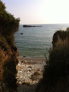 un chemin menant à une plage avec une île dans l'eau dans l'établissement Mare di l'angeli, à Lévktron
