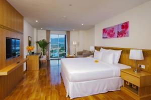 a hotel room with a large white bed and a television at Rosaka Nha Trang Hotel in Nha Trang