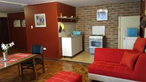 a living room with a red couch and a kitchen at Apartamento independiente a 6 minutos de Mall el Jardín in Quito