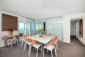 a dining room with a white table and orange chairs at Private Apartment with Ocean Views at Q1 Resort in Gold Coast