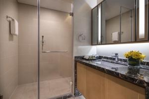 a bathroom with a glass shower and a sink at Somerset Harmony City Wuxi in Wuxi