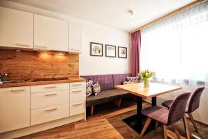 a kitchen with white cabinets and a table and chairs at Amaris Apartments in Ischgl