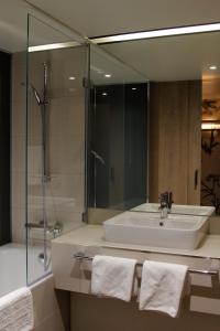 a bathroom with a sink and a shower and a mirror at Sorat Hotel Saxx Nürnberg in Nürnberg