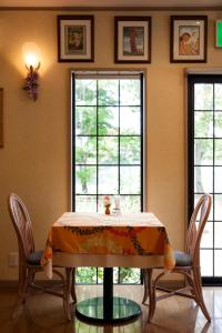 a dining room with a table and two windows at ペンションカパルア軽井沢 in Karuizawa