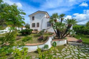 ein weißes Haus mit Palmen im Hof in der Unterkunft B&B Li Fringi in Torchiara