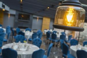 uma sala com mesas e cadeiras azuis e um candeeiro em Greymark Hotel em Esmirna