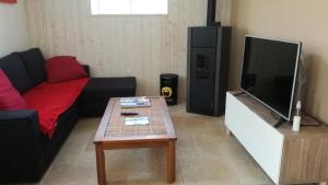 Una sala de estar con un sofá y un televisor de pantalla plana. en Le petit paradis, en Daumeray