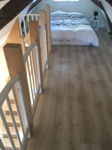 Un dormitorio con una cama y suelo de madera. en Le petit paradis, en Daumeray 4 fotos más