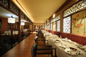 a dining room with long tables and chairs and windows at The Residency Towers Coimbatore in Coimbatore